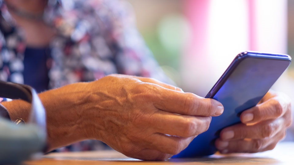 Äldre kvinna håller i en telefon