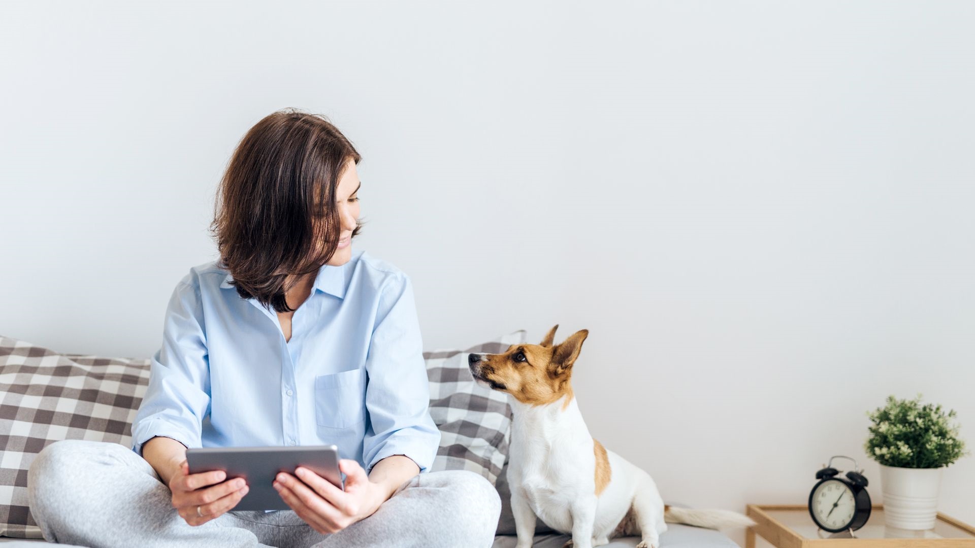 Kvinna som håller i en iPad medan hon tittar på en hund